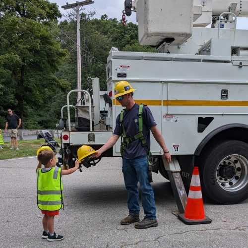 A SELCO lineman showing a hard hat to a young boy.